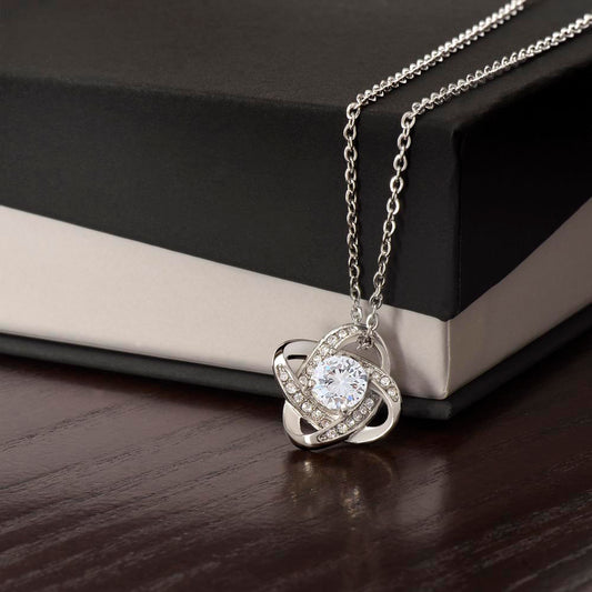 Silver Love Knot pendant close-up on two-tone gift box